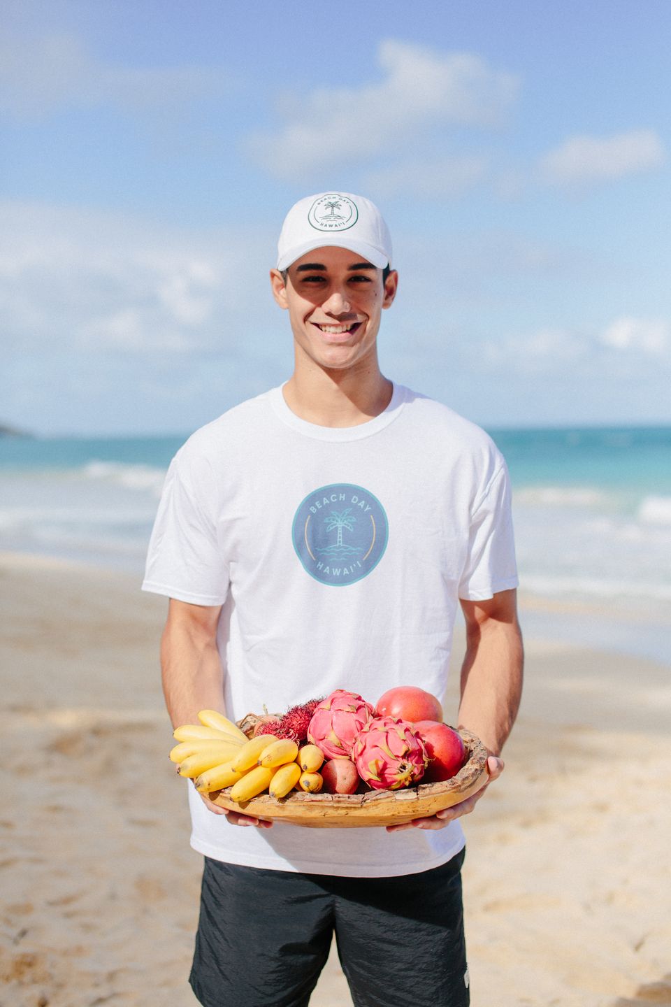 Beach Day host holding a tray of tropical fruit by the shoreline